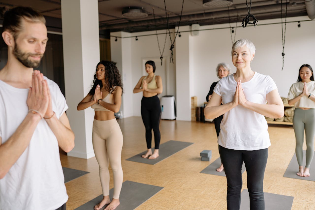 expertise-01 A group of diverse adults meditating and performing yoga in a studio.